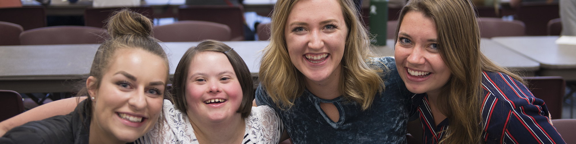Students sit with a girl with Down syndrome.